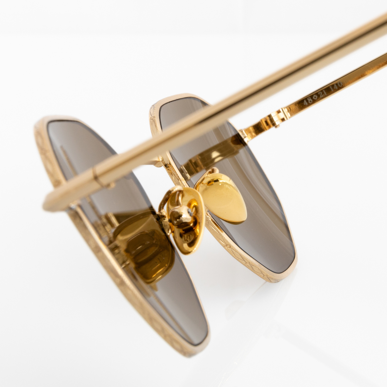 Gold hexagon Memorí sunglasses with warm brown lenses. Macro view to show gold nose pads and geometric pressed edge detailing. Narrow width. Best sunglasses for small faces. Made in Italy.