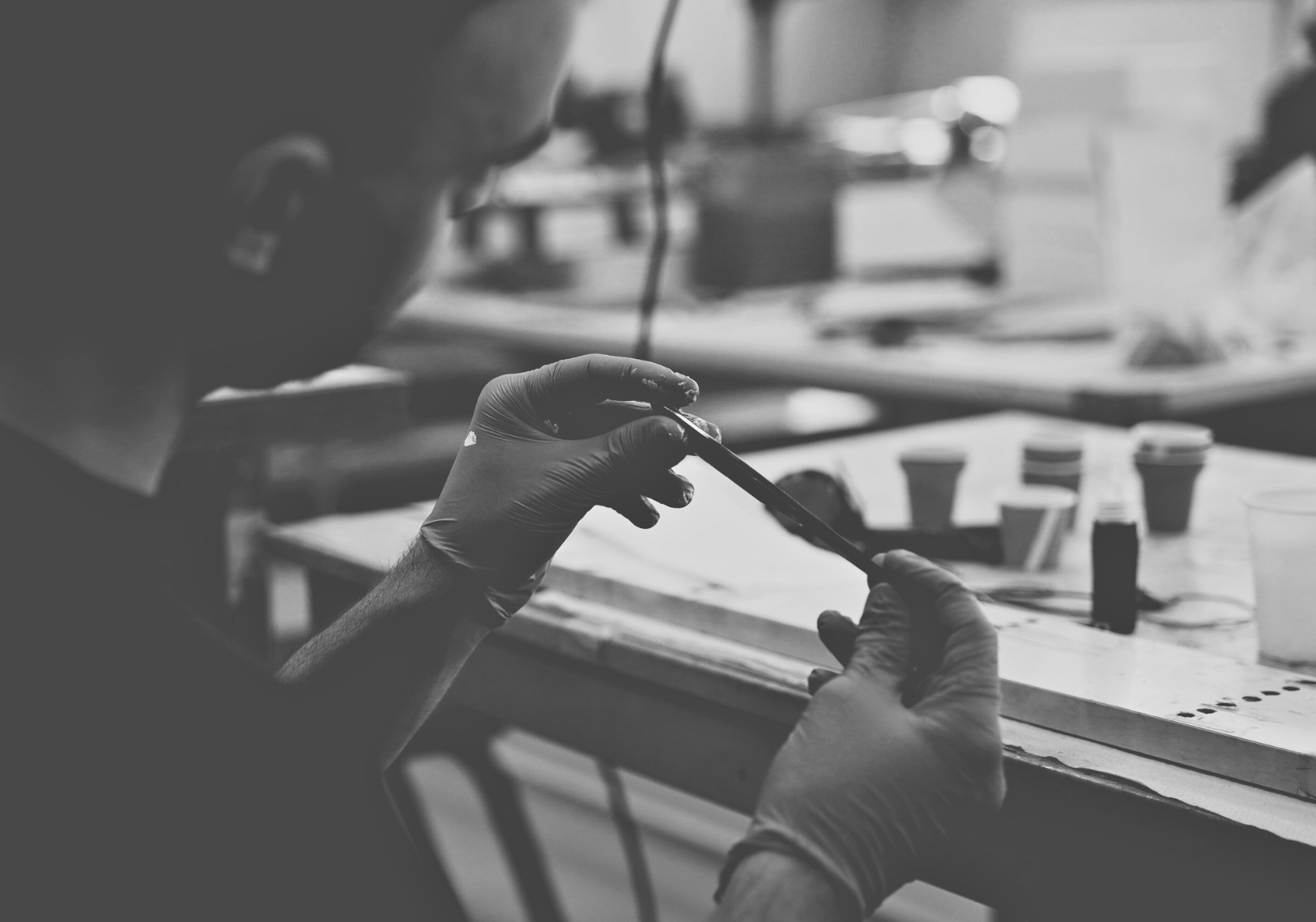 Italian worker in the process of applying logo under lacquer to the temple arm of a pair of Memorí sunglasses