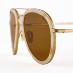 Aviator sunglasses for small faces gold frame, macro view which shows geometric detail pressed into metal rims, mazzucchelli acetate rim sheaths, and Memorí logo in corner of lens