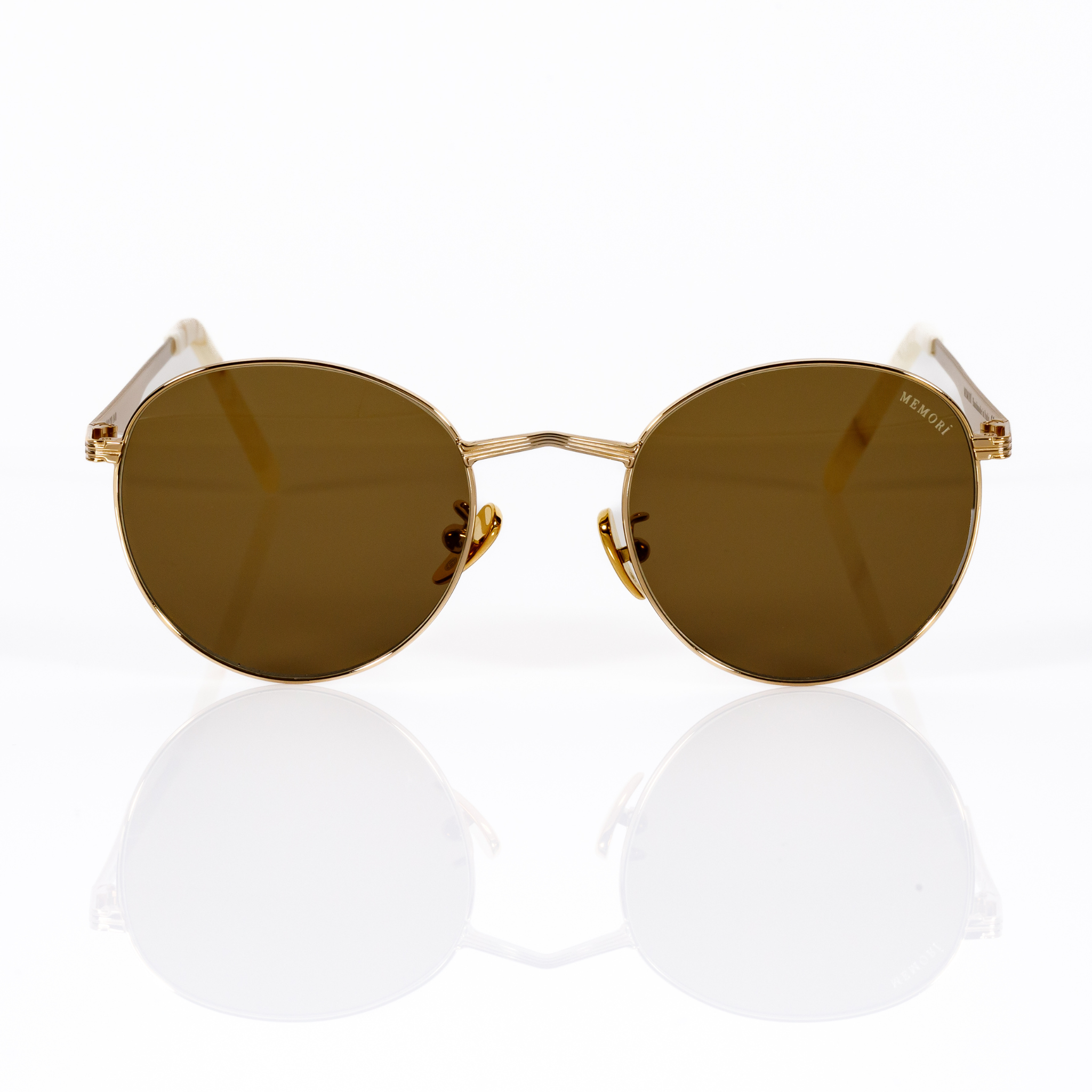 Front view of Memorí round sunglasses in gold with warm brown lenses. Angular V shaped nose bridge is featured as well as Memorí logo on upper right hand corner of lens. Small fit sunglasses designed specifically for petite and narrow faces. Best sunglasses for small faces. 