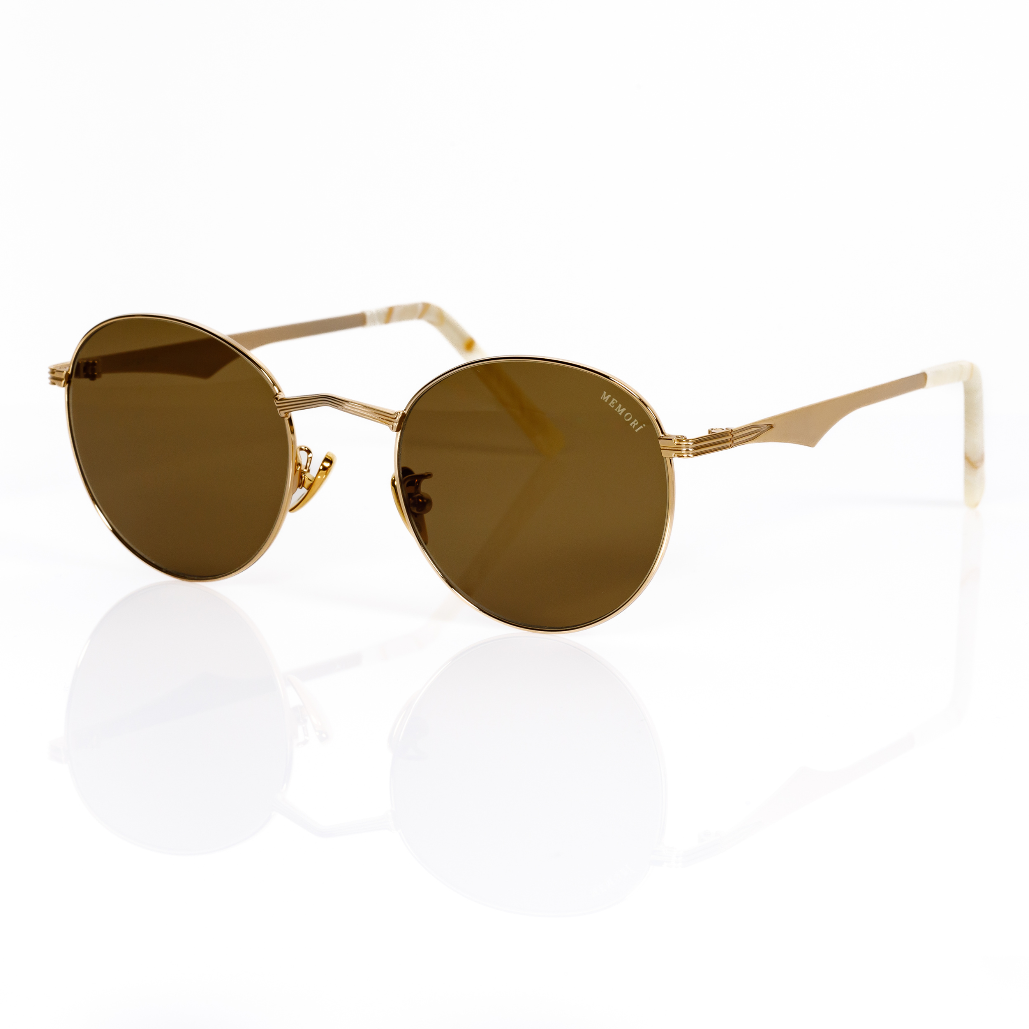 Memorí sunglasses are the best sunglasses for small faces, as every pair is designed with a narrow fit. This photo shows the Rounc sunglasses in gold with warm brown lenses, and showcases the angular nose bridge and scalloped temple arms. 
