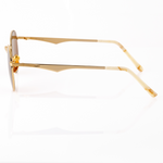 profile side view of Memorí gold round sunglasses with warm brown lenses. Side view shows the scalloped temple arm and linear wrap-around hinge detail. Temple Tips are mazzucchelli acetate in an ivory marbled color. 