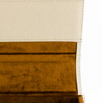 Macro view of the materials and textures of this protective leather eyewear case. Leather has a pebbled texture, and is a cream/ivory color. Inner lining is soft brown velvet, to not scratch the sunglass lenses. The photo depicts a luxurious product that is both fashion forward, and practical to protect eyewear investment.