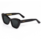 3/4 view of Memori black cat eye sunglasses. The design is sleek and elegant. This view shows of the top beveled edge, and the gold laurel dealing inside the temple arm. Memori logo in gold also appears as a small metal badge set into the acetate on the external temple arm.