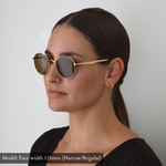 Model with 128mm width face (which falls into Narrow/Regular category) wearing the gold round Memorí sunglasses with brown lenses. 3/4 view shows temple design details. Designed specifically to fit narrow faces.