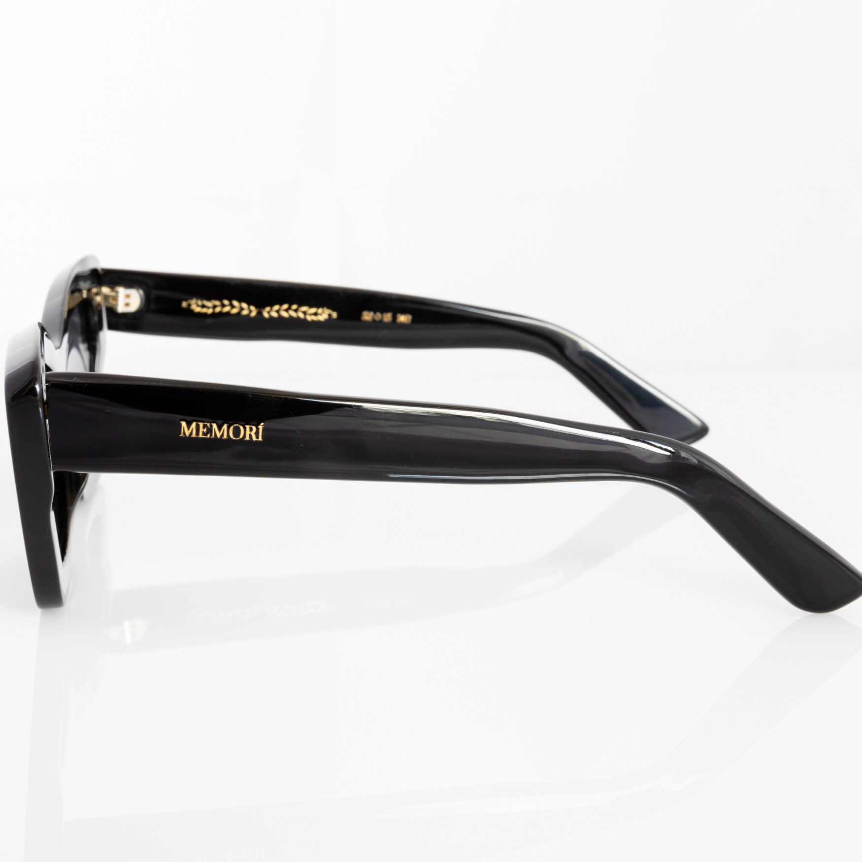 Black polarized cat eye sunglasses - side profile view shows Memorí logo in gold on external temple arm, and gold foil laurel design on internal temple as a design detail. Designed to have smaller fit for narrow faces. 
