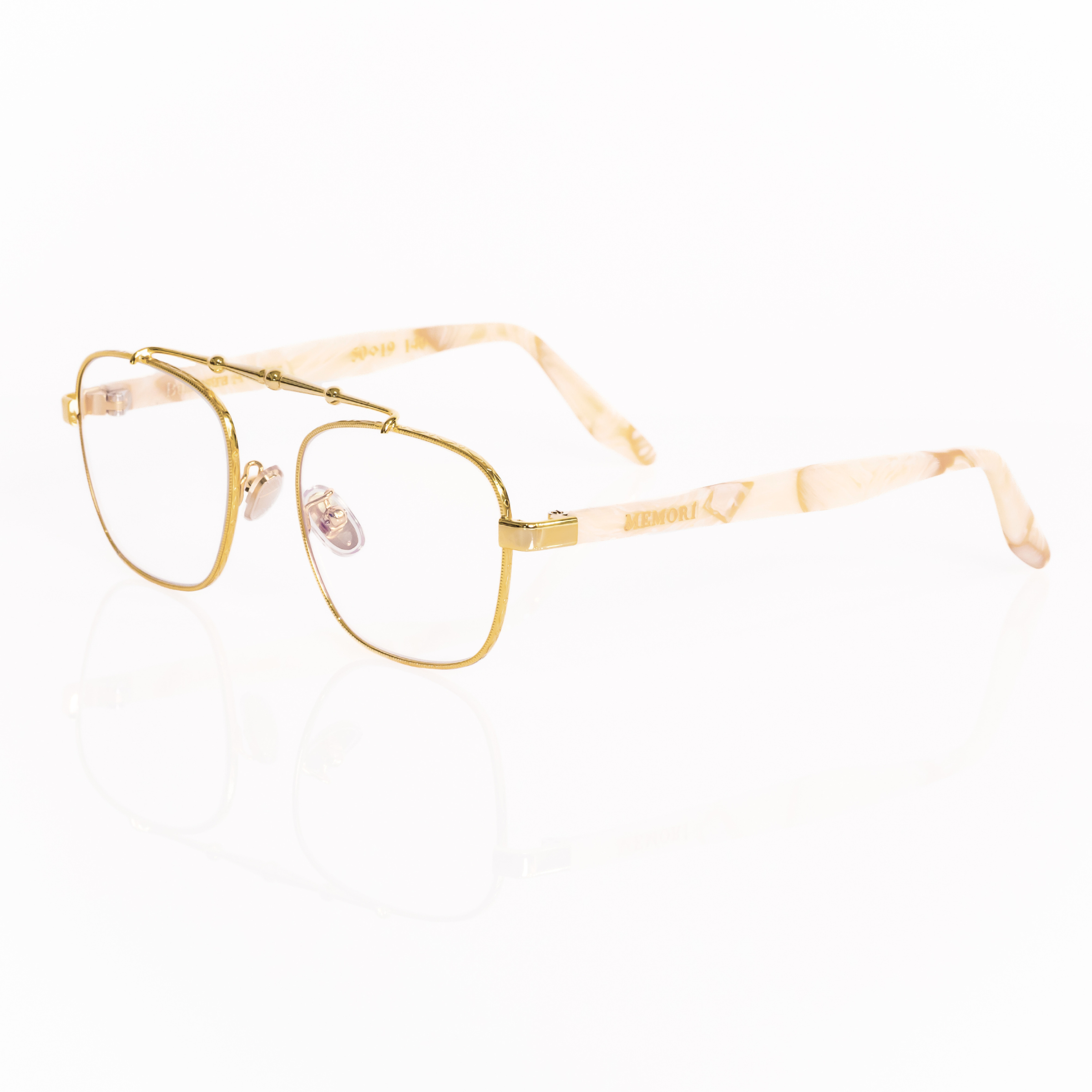 Balaustra aviator optical frames viewed from he corner. gold metal frame with marbled ivory and light brown acetate temple arms.  "Memori" logo in gold is visible inlaid into the acetate arm. Nose pads are gold with silicone cover. 