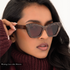 Woman wearing sunglasses with a maroon, gray and cream colored marbling pattern for the frame and maroon tinted lenses. Frame silhouette is a subtle cat-eye shape that appears very elegant. 