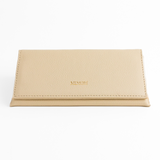 Photo of Memorí hardshell leather sunglass case. Case has an elegant, triangular design and is made of a textured, cream colored leather. Memori logo is embossed in small gold foil letters on the front of the flap. This eyewear case is very protective and would be suitable to protect luxury sunglasses in a suitcase or other environment subject to pressure. 