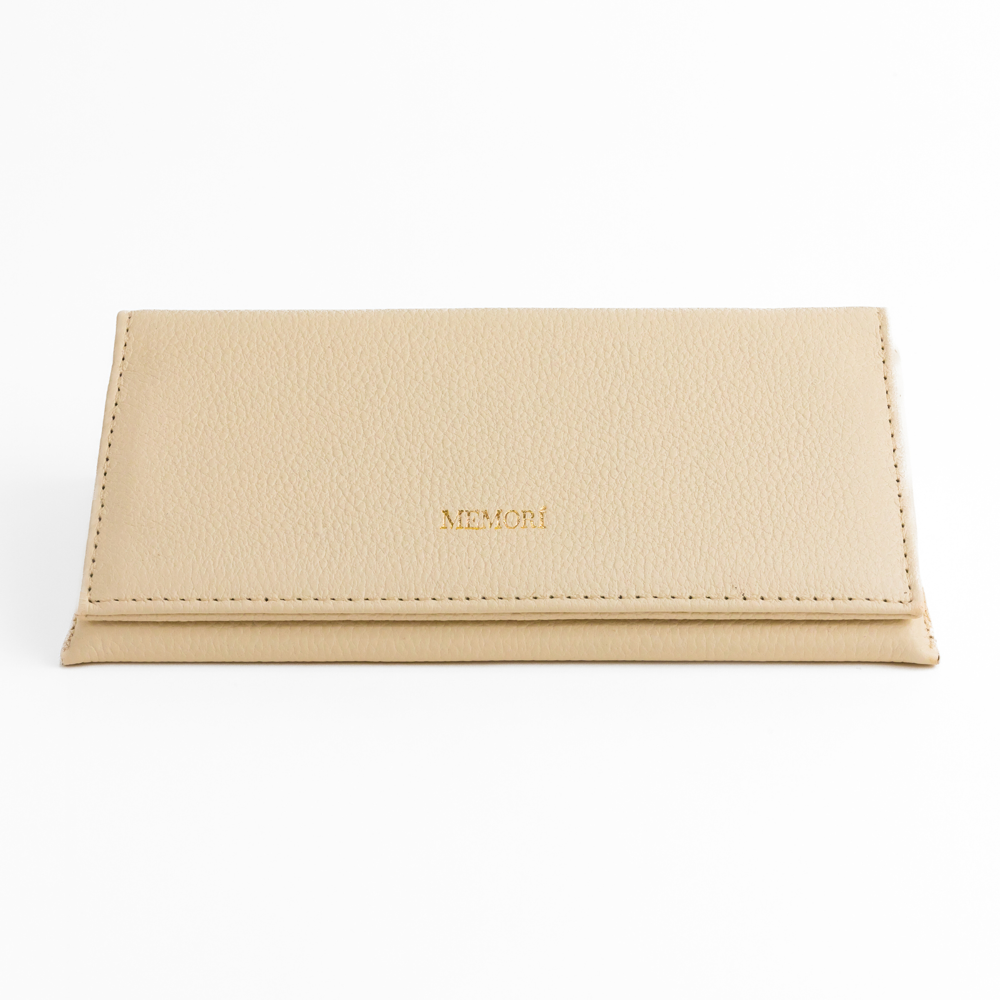 Photo of Memorí hardshell leather sunglass case. Case has an elegant, triangular design and is made of a textured, cream colored leather. Memori logo is embossed in small gold foil letters on the front of the flap. This eyewear case is very protective and would be suitable to protect luxury sunglasses in a suitcase or other environment subject to pressure. 