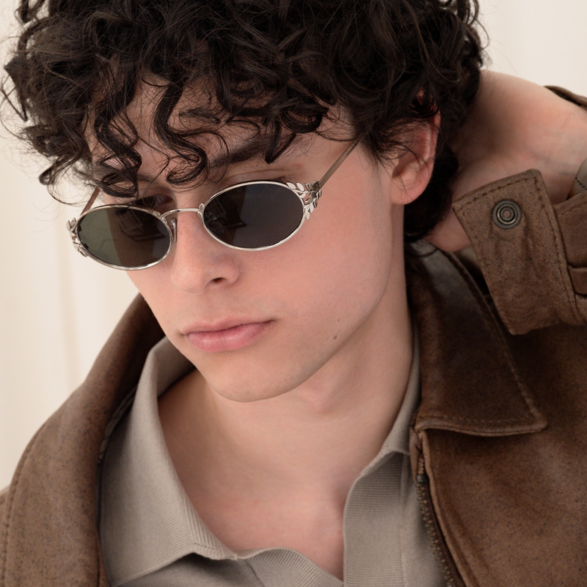 Male model wearing silver laurel oval sunglasses with green lenses. 