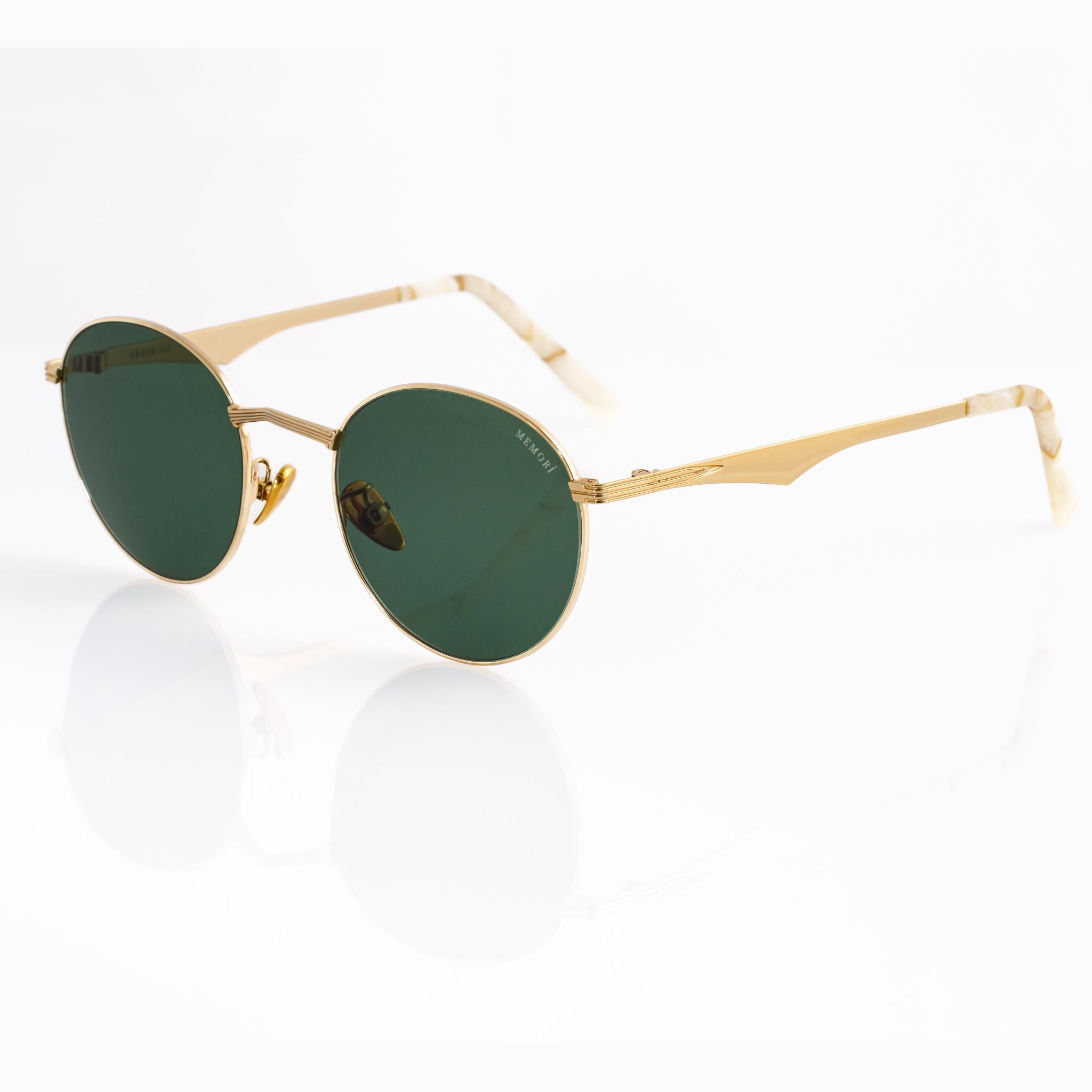 Gold framed sunglasses with round lenses in a dark green color on a white background. 3/4 angle shows scalloped design of metal temple arm and white marbled temple tips. 