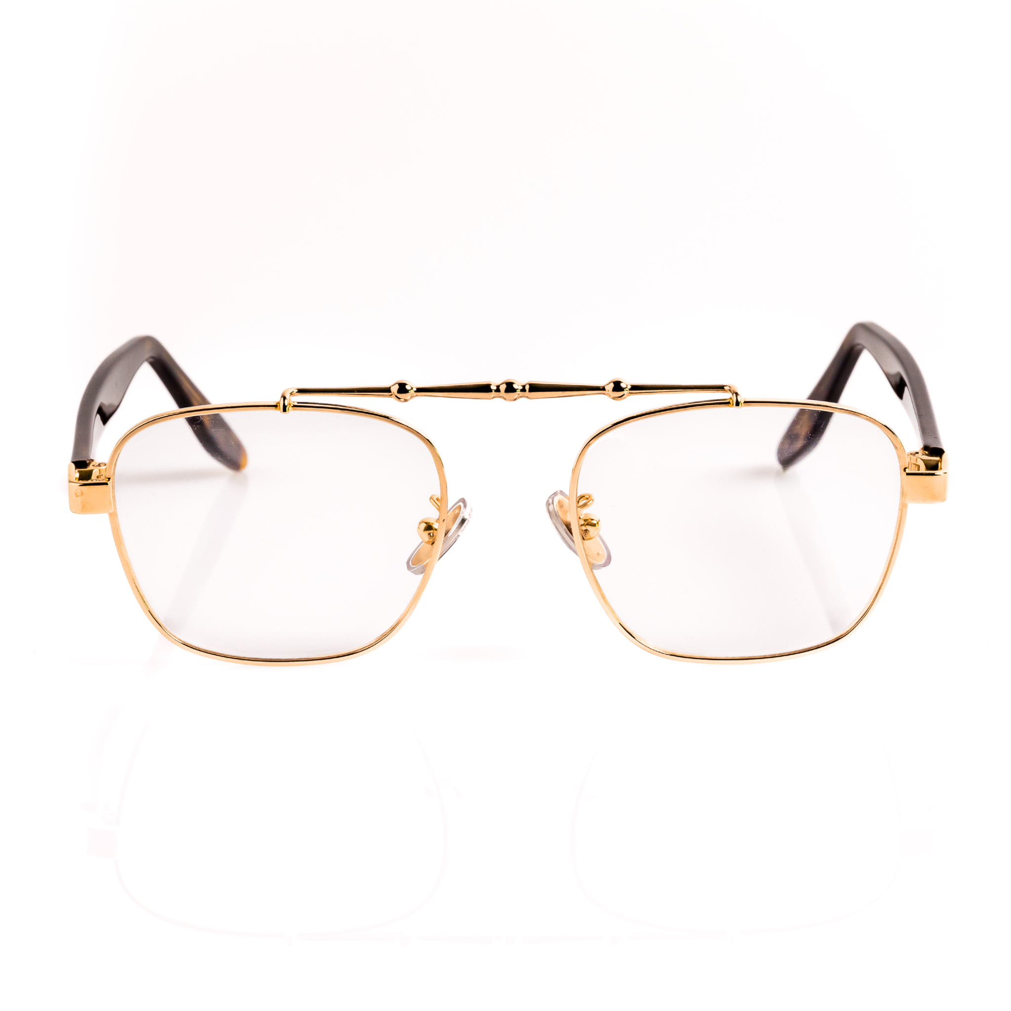 gold, metal frame blue light blocking glasses with transparent lenses, tortoise temple arms and a detailed metal upper brow bar on a white background. 