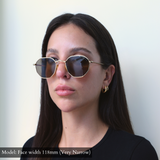 Model with very narrow face wearing Memorí gold hexagon frames with warm brown lenses. Best Sunglasses for small faces. 