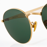Detail shot of the metal nose bridge of a gold metal pair of sunglasses. Features a "V" shaped nose bridge which appears to be a design inspired by architectural columns, and gold nose pads which are adjustable. 