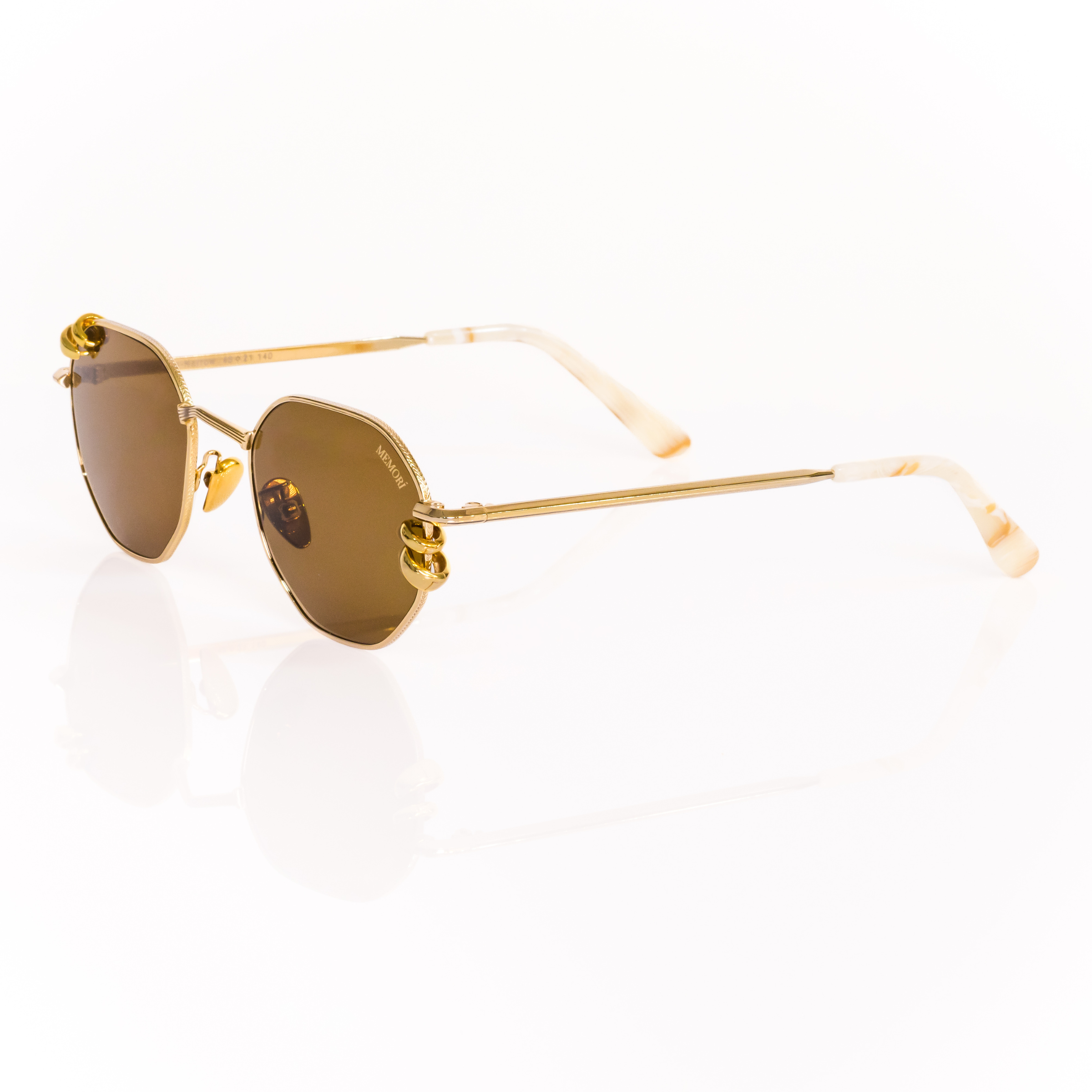 Gold metal sunglasses with brown lenses on a white background. 3/4 view shows chunky gold hoop piercings through the lenses. Pierced sunglasses. Ivory Marbled acetate temple tips. 