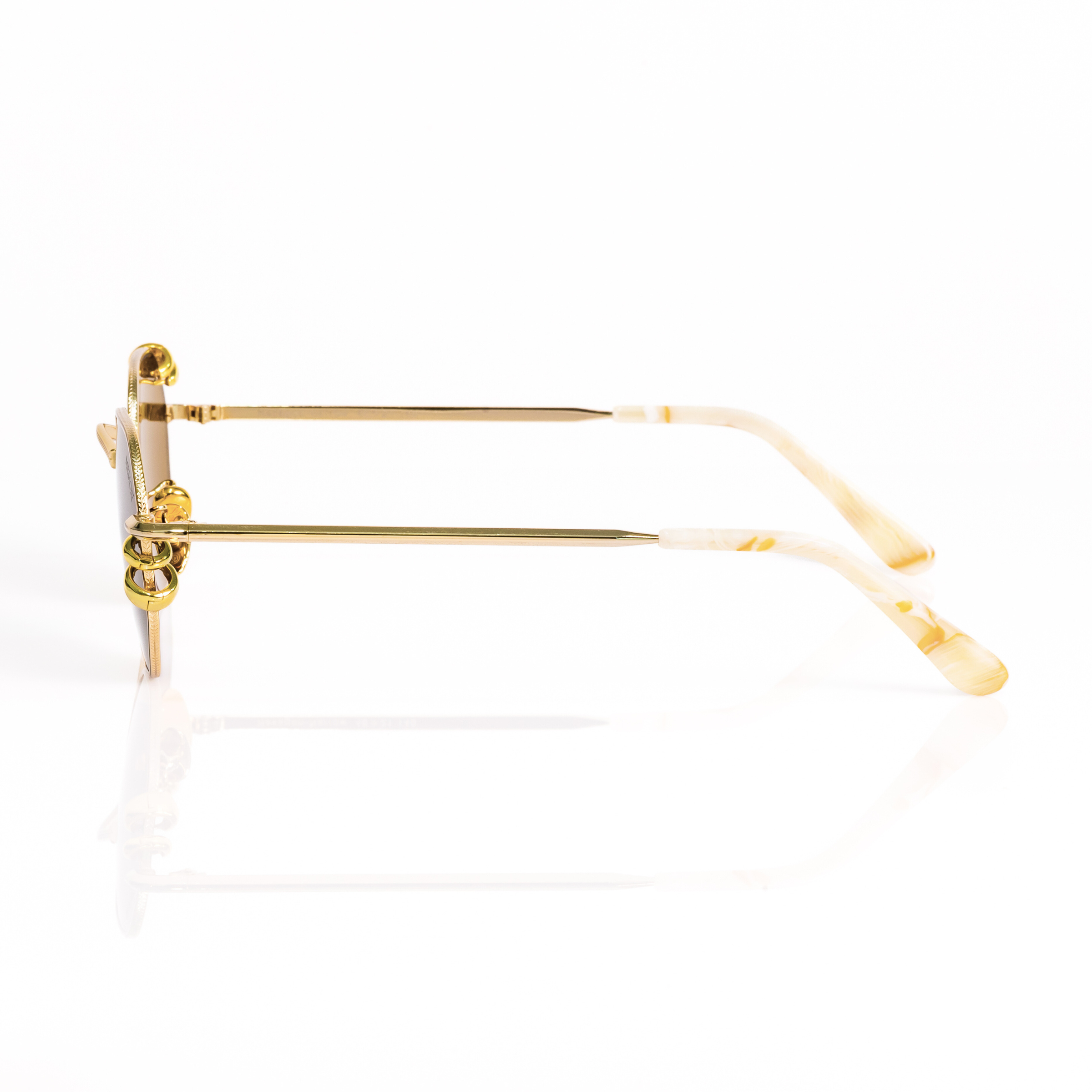 Profile view of the memori pierced hexagonal sunglasses. ivory marbled temple tips and gold hoop piercings attached to the external edge of the lens are visible. 