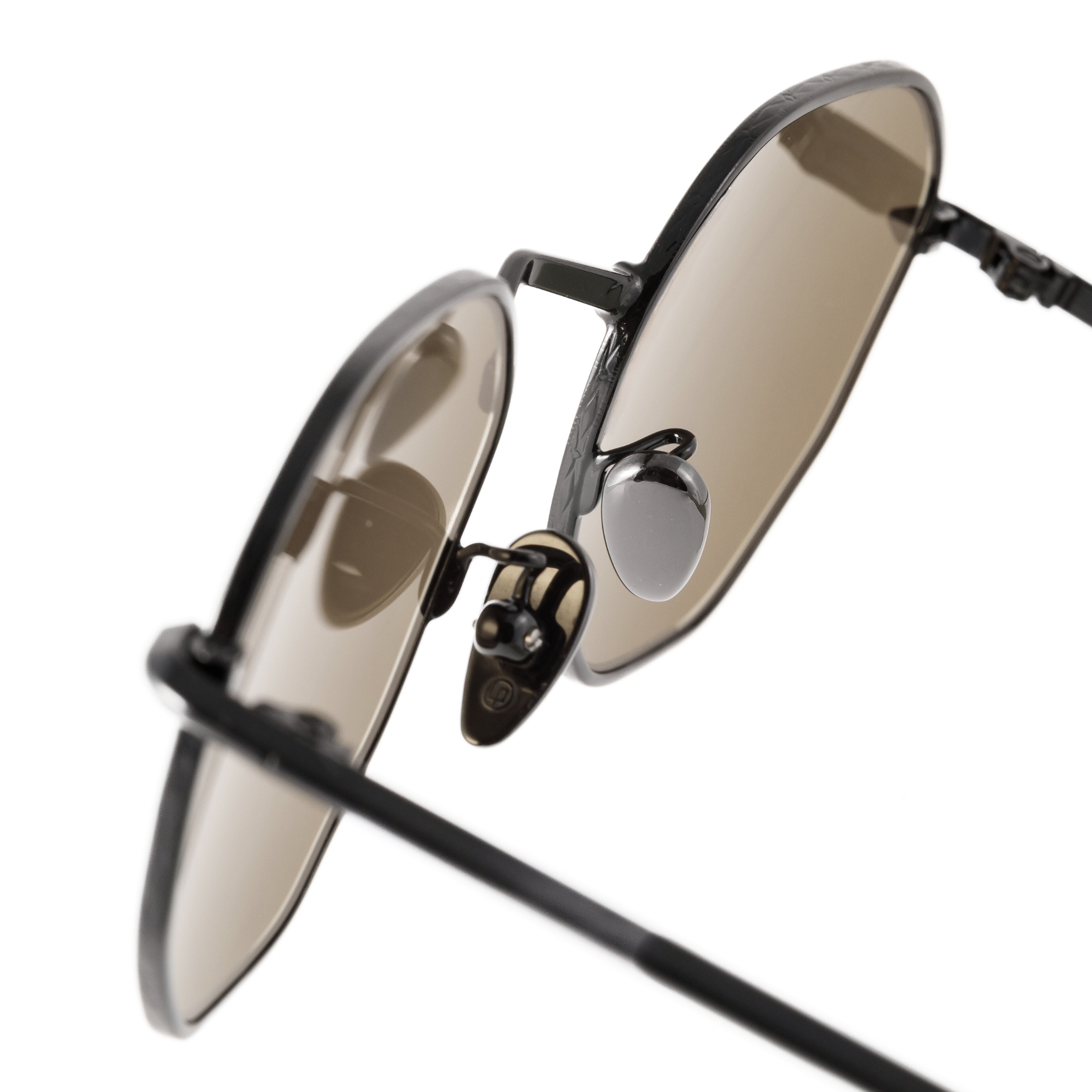 macro view of the intricate details on memori sunglasses, including repeating diamond pattern around rim and metallic ceramic nose pads that appear black to match the monochromatic black frame